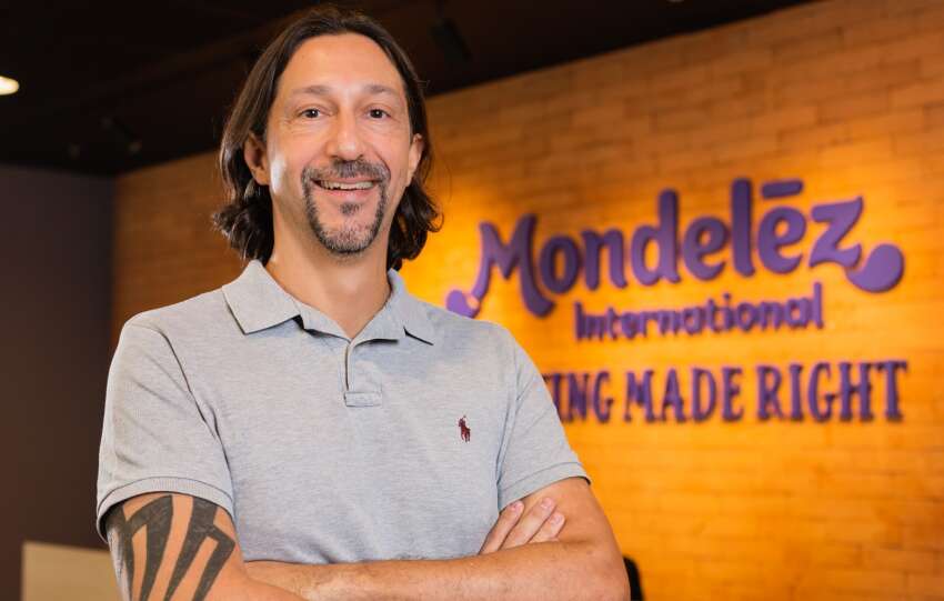 Alvaro Garcia, CMO da Mondelez, de braços cruzados, em frente à parede com a marca